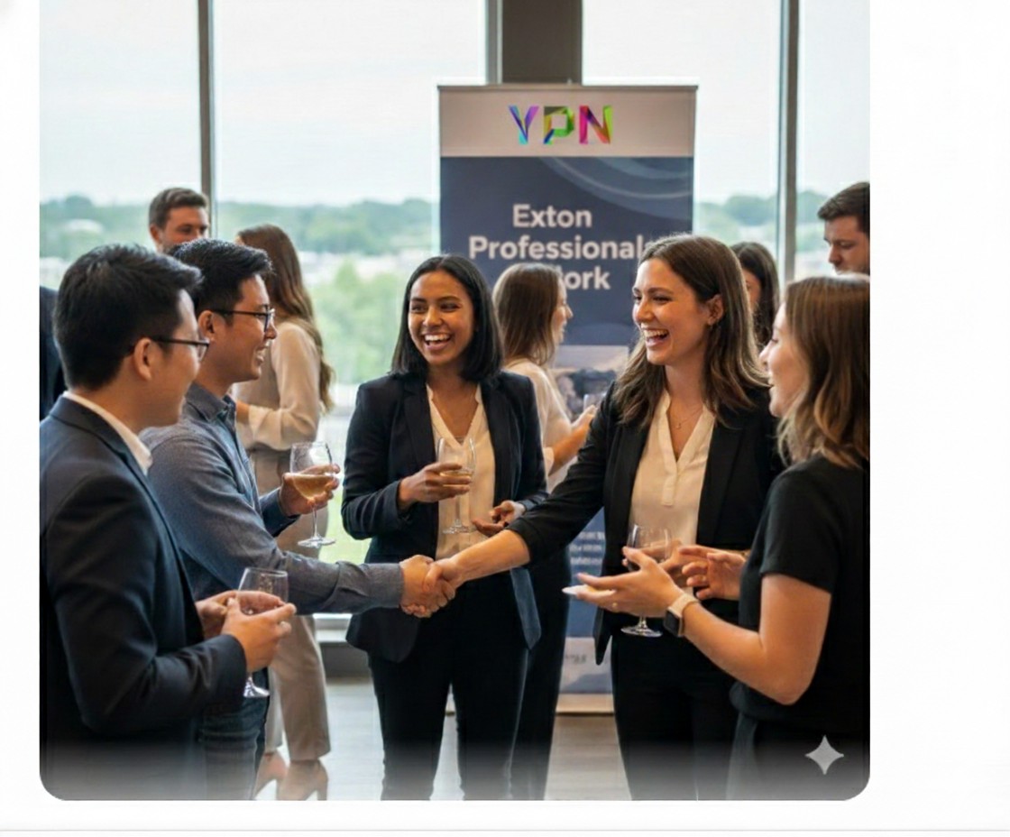 A group of professionally dressed people stand in a bright room, talking, smiling, and shaking hands at a networking event. A banner in the background reads "Exton Professional Network.